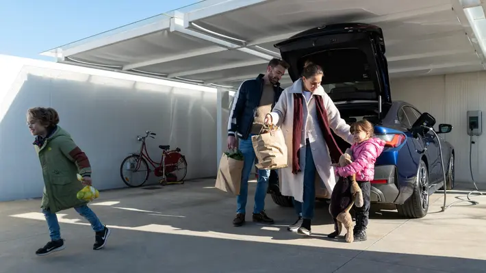 Familie vor einem ladenden E-Auto